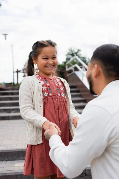 Усміхнена азіатська дитина тримає руку батька в парку — стокове фото