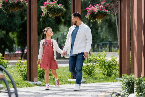Happy asian family holding hands while walking in park — Stock Photo