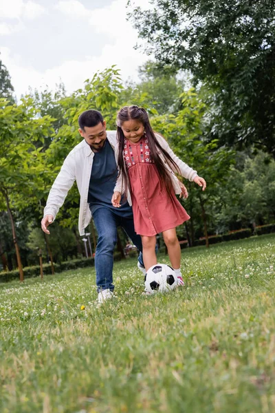 Asian family playing soccer on grass in summer park — Photo de stock