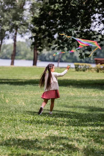 Азиатская девушка играет с разноцветным летящим змеем в летнем парке — стоковое фото