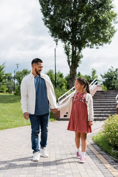 Asian parent and kid holding hands while walking in summer park — Fotografia de Stock