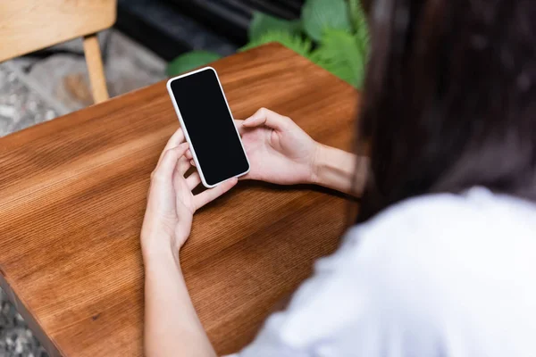 Blurred woman using smartphone in cafe outdoors — Stockfoto