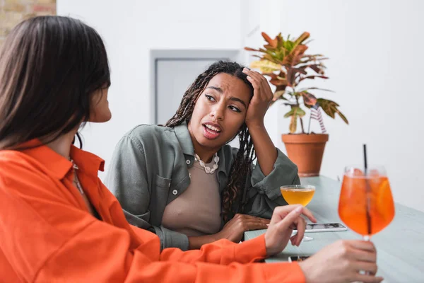 African american woman talking to girlfriend near cocktails and smartphones in cafe — Photo de stock