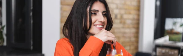 Positive woman holding drinking straw of cocktail in cafe, banner — Stock Photo