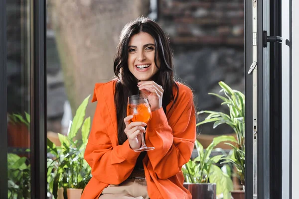 Веселая женщина с коктейлем у окна в кафе — стоковое фото