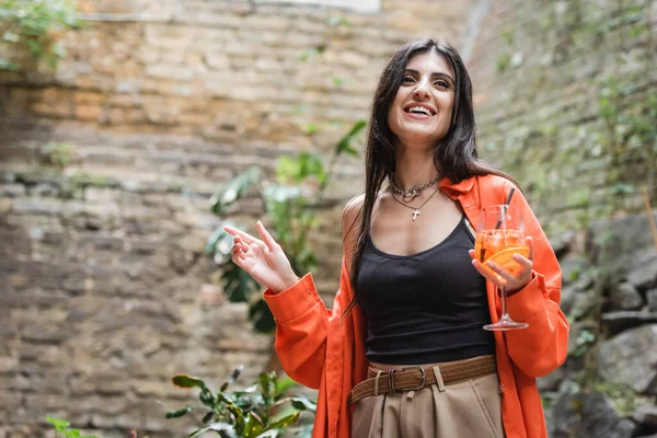 Low angle view of smiling woman holding cocktail on terrace of cafe — Stockfoto