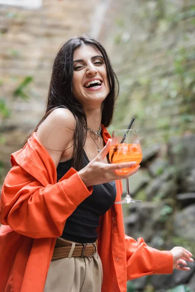 Positive woman holding glass of cocktail on terrace of cafe — Stock Photo