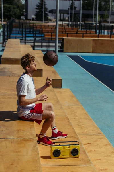 Вид збоку спортсмен грає з м'ячем, сидячи на стадіоні поблизу рекордного гравця — стокове фото