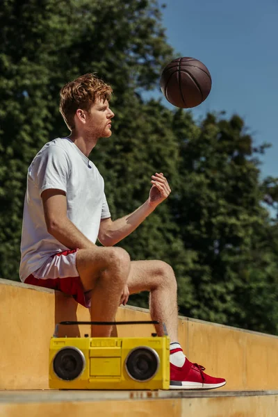 Redhead man playing with ball while sitting near boombox — Fotografia de Stock