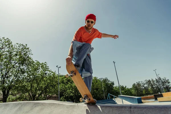 Young and stylish skateboarder jumping from ramp in skate park - foto de stock