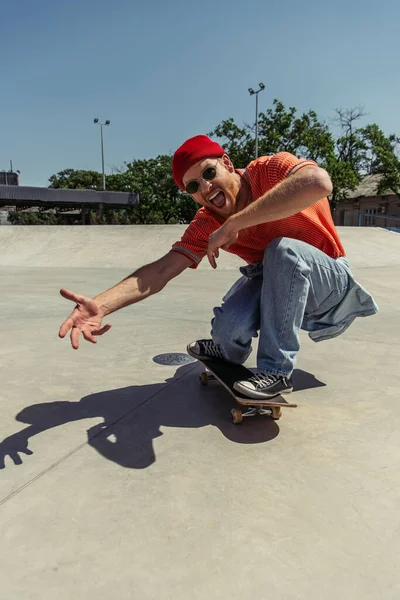 Чудовий чоловік жестикулює під час скейтбордингу в парку — стокове фото