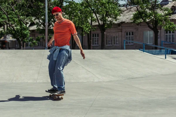 Trendy man in sunglasses riding skateboard in urban park — Stock Photo