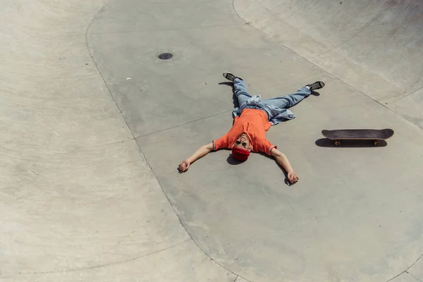 High angle view of cheerful man relaxing near skateboard on ramp — Stock Photo