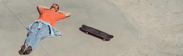 High angle view of trendy skater relaxing near skateboard, banner — Stock Photo