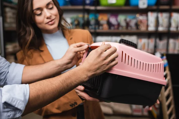 Man holding animal cage near blurred girlfriend in pet shop — Stock Photo