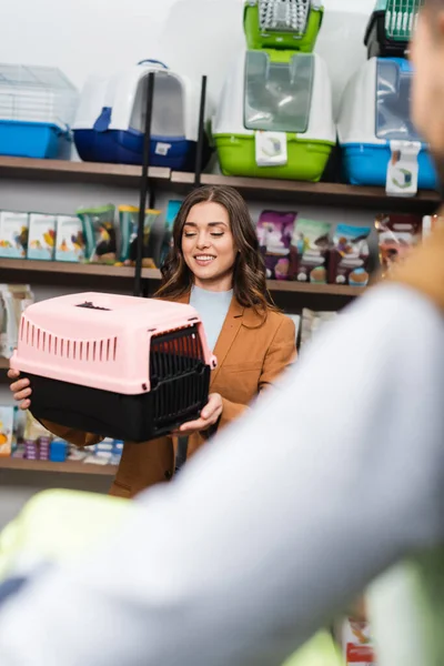 Cheerful woman holding animal cage near blurred boyfriend — Stock Photo