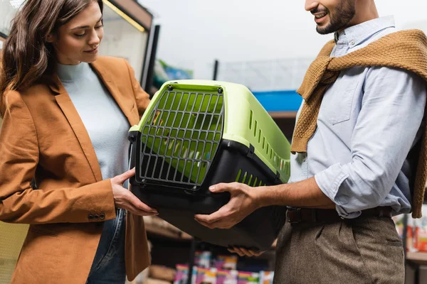 Cheerful man and woman choosing animal cage in pet shop — Stock Photo