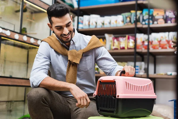 Smiling muslim man looking at animal cage in pet shop — Stock Photo