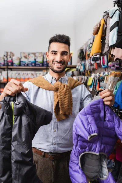 Positive muslim man holding animal jackets in pet shop — Photo de stock
