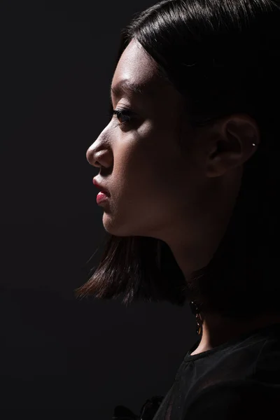 Side view of pretty and young asian woman looking away isolated on black — Stock Photo