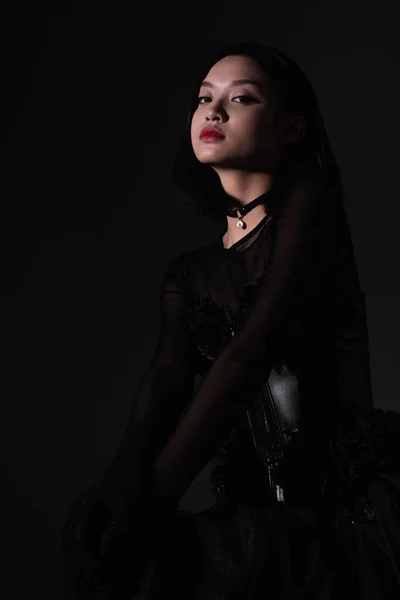 Portrait of young asian woman in gothic outfit with corset isolated on black — Stockfoto