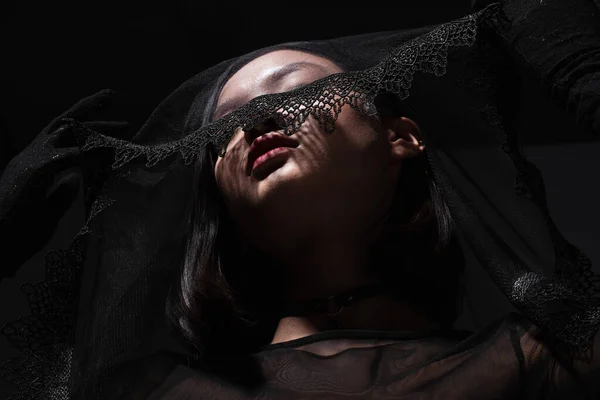Low angle view of young asian woman in black gloves holding black veil isolated on grey — Stock Photo