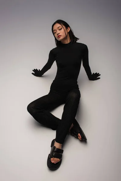 High angle view of stylish asian woman in total black outfit posing on grey — Fotografia de Stock