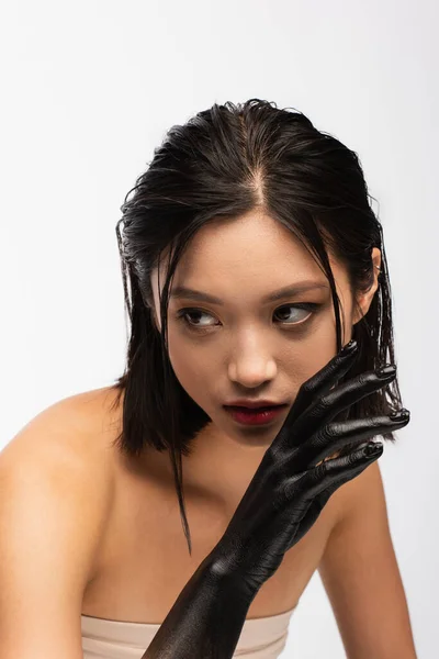 Young asian model with bare shoulders and hand in black paint posing isolated on white — Stock Photo