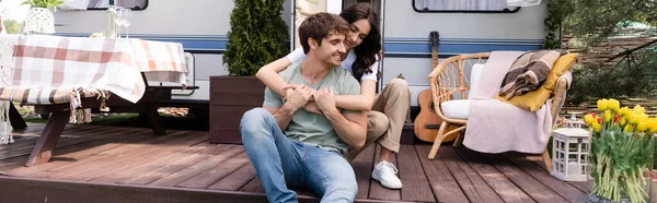 Young woman hugging smiling boyfriend near camper van outdoors, banner — Stock Photo