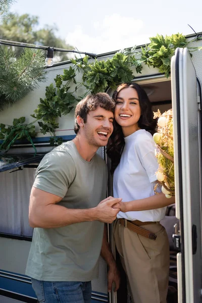 Весела пара тримає руки біля декору на дверях кемперського фургона — стокове фото