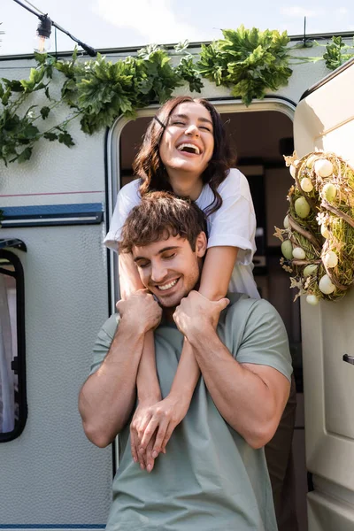 Cheerful woman hugging brunette boyfriend near decor on camper van — Stock Photo