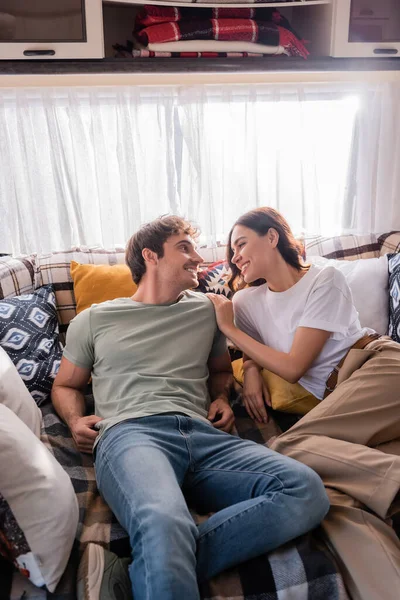 Smiling young couple lying on bed in camper van — Fotografia de Stock