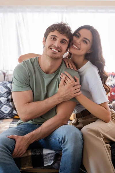 Smiling young couple hugging and looking at camera on bed in camper van — Foto stock