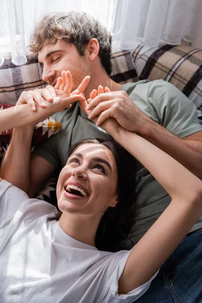 High angle view of smiling woman touching hands of blurred boyfriend on bed in camper van — Stock Photo