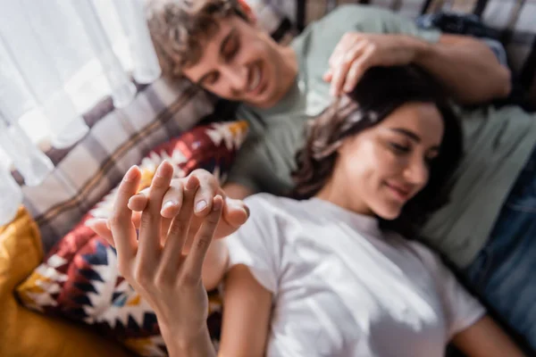 Top view of blurred young couple touching hands on bed in camper van - foto de stock