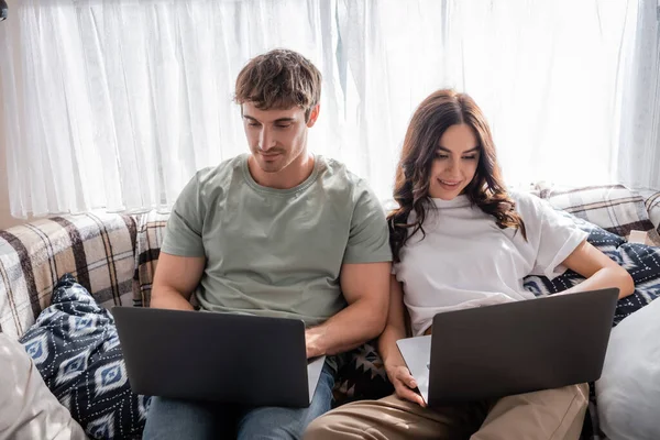 Young freelancers using laptops on bed in camper van — Stock Photo