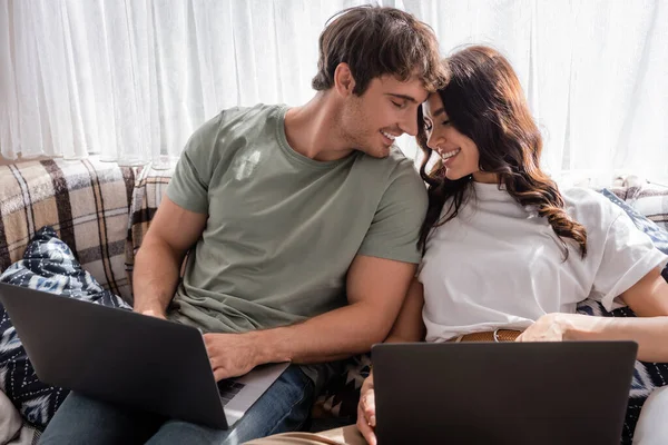 Positive couple using laptops on bed in camper van — Stock Photo