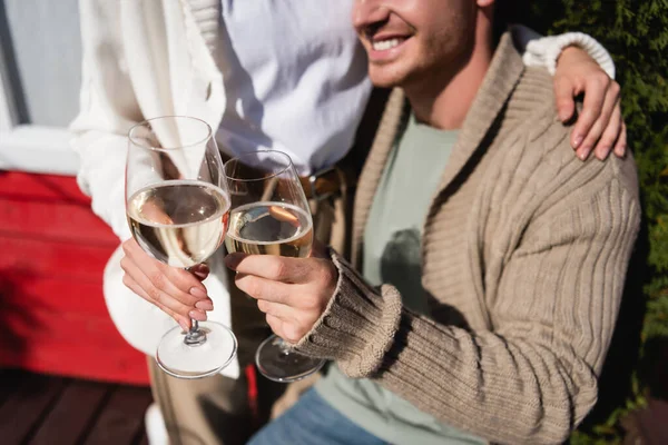 Cropped view of couple in warm cardigans toasting with wine outdoors — стоковое фото