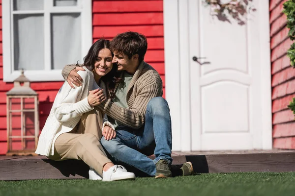 Cheerful young couple in cardigans hugging on terrace of house — Fotografia de Stock