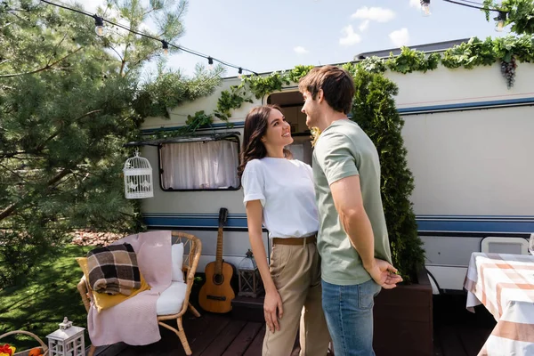 Smiling brunette couple standing on terrace near camper van — Stock Photo