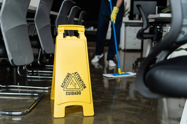 Vue recadrée du nettoyage flou plancher de lavage près panneau d'attention — Photo de stock