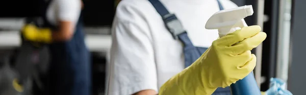 Partial view of blurred cleaner in rubber glove holding detergent, banner — Stock Photo