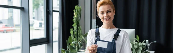 Glücklich professionelle Reinigungskraft zeigt leere Visitenkarte und blickt in Kamera, Banner — Stockfoto