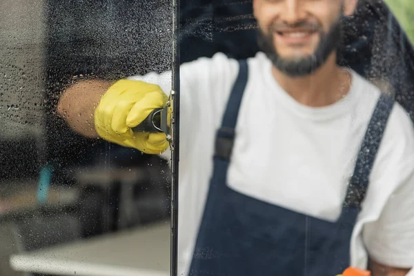 Обрезанный вид улыбающейся уборщицы моющее окно в офисе — стоковое фото