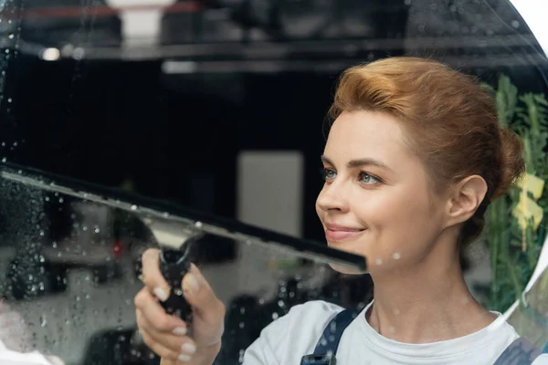 Happy professional cleaner smiling near wet window in office — Stock Photo