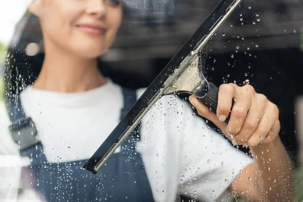 Vue partielle de la femme floue laver le verre avec raclette de fenêtre — Photo de stock