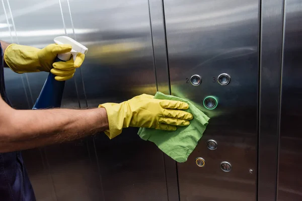 Partial view of man in rubber gloves cleaning metallic elevator — Stock Photo