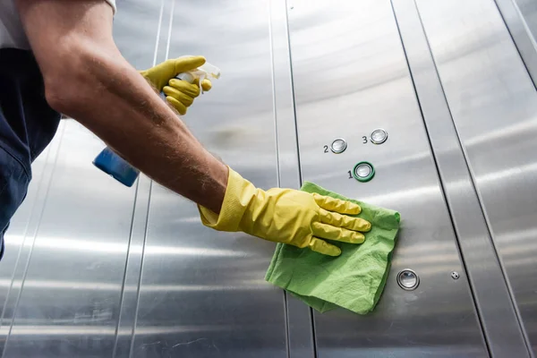 Cropped view of man in rubber gloves cleaning elevator with detergent and rag — Stock Photo