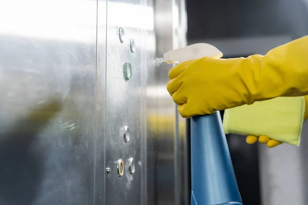 Vue partielle du détergent de pulvérisation plus propre pendant le lavage de l'ascenseur de bureau — Photo de stock