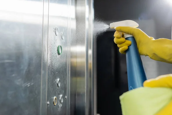 Visão parcial do homem pulverizando detergente durante a limpeza do elevador — Fotografia de Stock